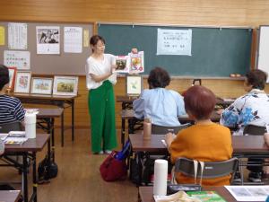講師が大人の塗り絵の本を見せている写真です。